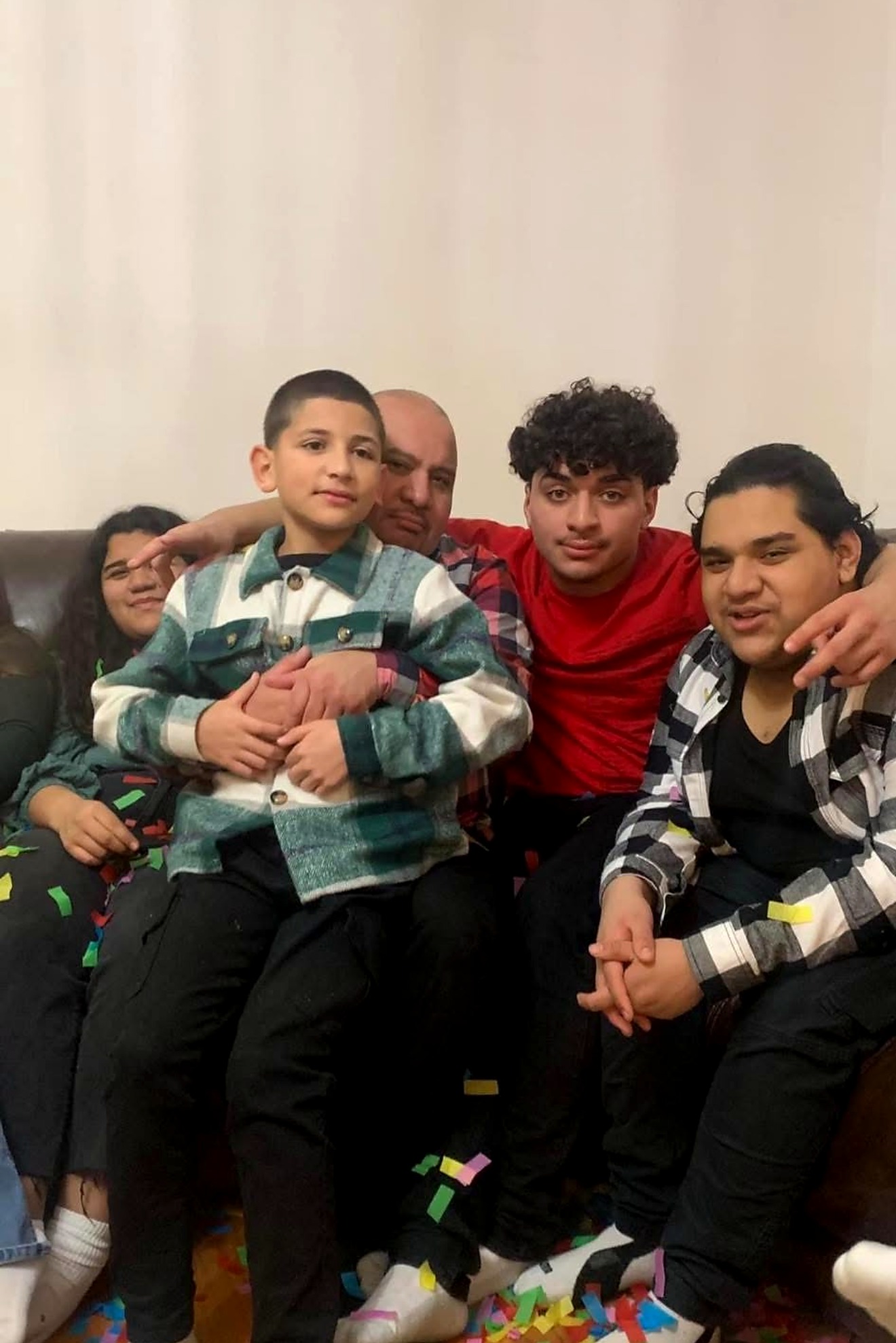 Elvis Escobar sitting on the couch surrounded by his sons and family